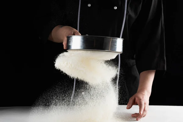 Темний фон пекарі руки просіяти біле пшеничне борошно над ситом — стокове фото