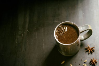 Gri arka planda kahve ve yıldız anason ve kakule kaplı metal termo bardak..