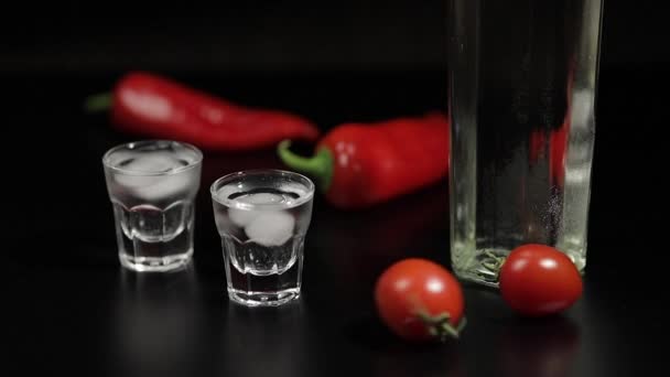 Körsbärstomat rulla upp till två koppar vodka. Svart bakgrund — Stockvideo