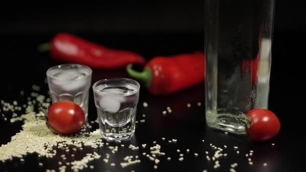 Spärliche Sesamsamen zu zwei Tassen Wodka in der Nähe von Flaschen mit Wodka — Stockvideo