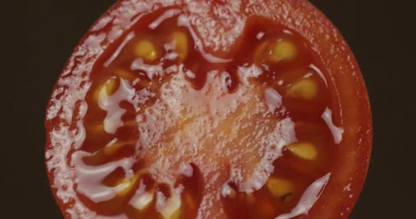 Gire las mitades de tomate fresco y maduro sobre un fondo oscuro — Vídeo de stock