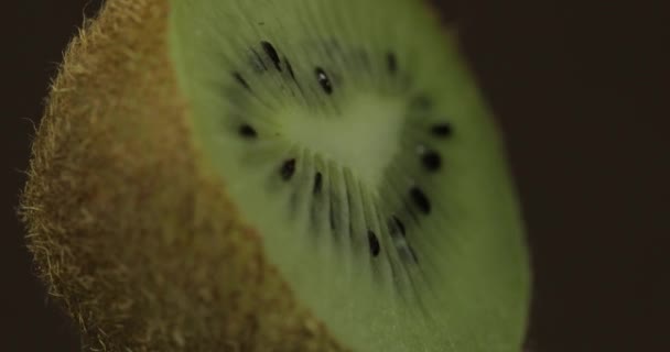 Girar la pieza de kiwi sobre un fondo oscuro — Vídeos de Stock