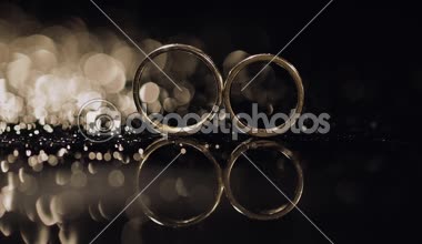 Alyans parlayan ışık ile karanlık yüzeyinde yalan makroyu kapatın. Yansıma. Siyah arka plan