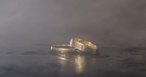 Свадебные Кольца Лежат Темной Поверхности Отражением Водой Шиннинг Макро Крупным — стоковое видео