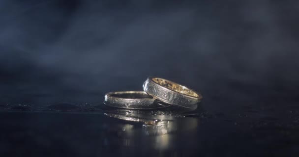 Wedding Rings Lying Dark Water Surface Shining Light Close Macro — Stock Video