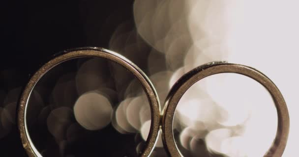 婚礼戒指躺在黑暗的表面上 闪耀着明亮的宏 黑色背景 — 图库视频影像