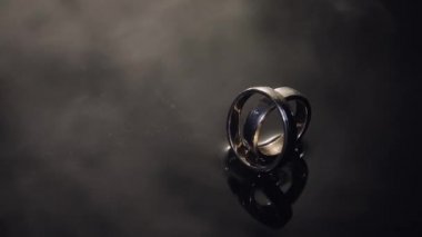 Karanlık su yüzey parlayan ışık ile üzerinde alyans. Makroyu kapat