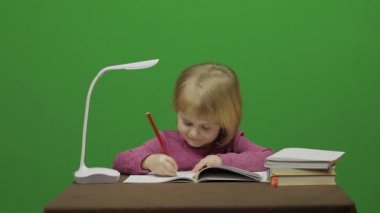 Kız masada çizim. Eğitim sürecinde sınıf. Mutlu üç yaşında bir kız. Sevimli kız gülümsüyor. Küçük çocuk, 3-4 yaşında sarışın kız. Yüzleri olun. Yeşil ekran video. Chroma Key
