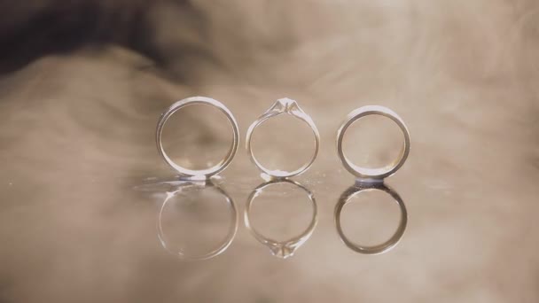 结婚戒指和订婚戒指躺在黑暗的水面上 闪耀着明亮的宏观 — 图库视频影像