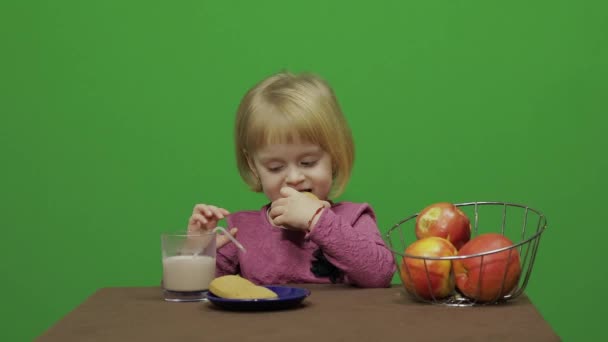 Κορίτσι Κάθεται Στο Τραπέζι Και Τρώει Σοκολάτα Μπισκότα Μήλα Ευτυχισμένος — Αρχείο Βίντεο