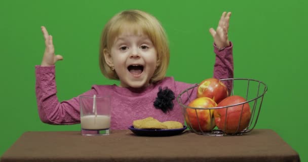 Κορίτσι Κάθεται Στο Τραπέζι Και Τρώει Σοκολάτα Μπισκότα Μήλα Ευτυχισμένος — Αρχείο Βίντεο