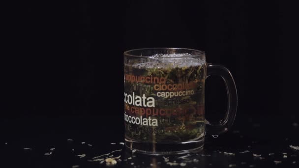 グリーン ティー 有機乾燥緑茶とグラスの葉お湯のカップの中を浮遊しています スローモーション — ストック動画