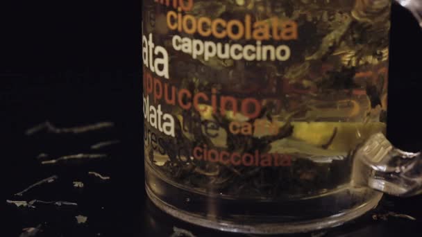 杯子与有机干绿茶叶和柠檬片 漂浮在杯子内的热水 慢动作 黑色背景 — 图库视频影像