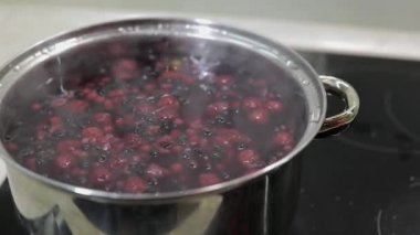 Çilek tencerede kaynar su ile. Şeker ekleyerek. Komposto yemek. Mutfak