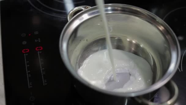 Leite sendo derramado na panela de aço inoxidável para cozinhar na cozinha — Vídeo de Stock