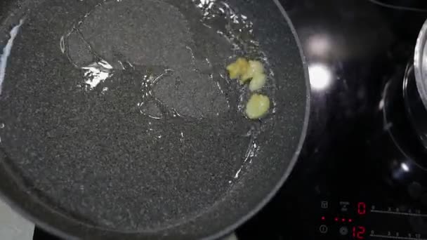 Fried sliced garlic and boiling food oil in the black pan — Stock Video