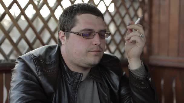 Бизнесмен расслабляется и курит сигарету на террасе. Говоря взволнованно — стоковое видео