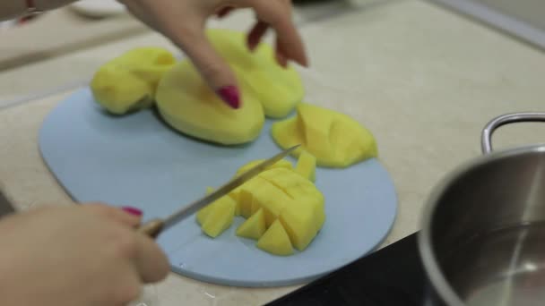 Femme coupant la pomme de terre sur la planche à découper bleue — Video