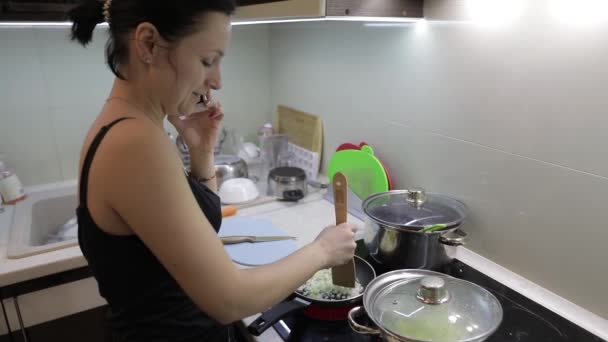 Hermosa mujer caucásica hablando por teléfono mientras cocina — Vídeos de Stock