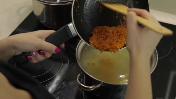 Geriebene Karotten in einen Topf mit Kartoffelsuppe und Fisch geben — Stockvideo