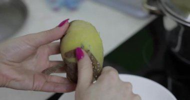 Kadın ev kadını mutfakta Soyma patates eller.