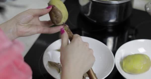 Mulheres dona de casa mãos descascando batatas na cozinha . — Vídeo de Stock