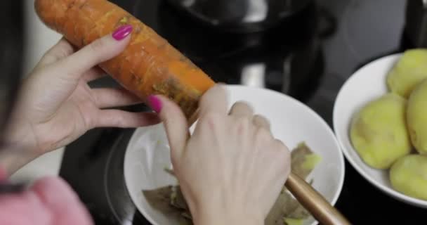 Mulheres dona de casa mãos descascando cenoura na cozinha . — Vídeo de Stock