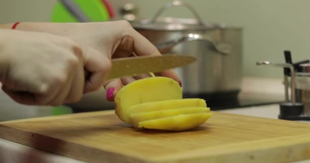 Női háziasszony kezek burgonya szeletelő darabokra a konyhában — Stock videók