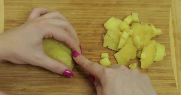 Домохозяйка разрезает картошку на куски на кухне. — стоковое видео
