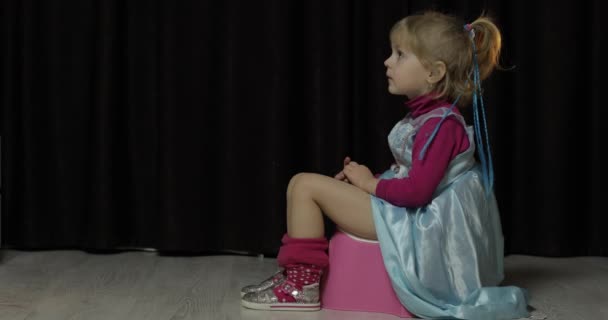 Маленькая девочка сидит на горшке и смотрит телевизор — стоковое видео