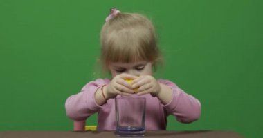 Güzel genç kız limon suyu sıkar ve yüzünde bir yüz buruşturma ile içecekler