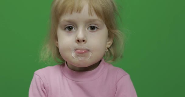 Chica sentada en la mesa y bebe leche de yogur. Divertido bigote de leche — Vídeos de Stock