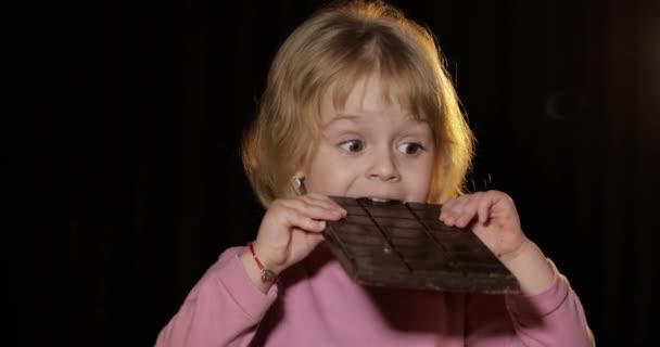 Attractive child eating a huge block of chocolate. Cute blonde girl — Stock Video