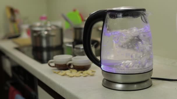 Wasserkocher mit kochendem Wasser vorhanden. Teebeutel und Zucker auf dem Hintergrund — Stockvideo