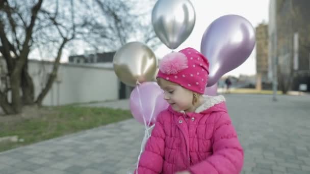 Šťastné roztomilé dítě na ulici s balónky s héliem. Oslava narozenin — Stock video