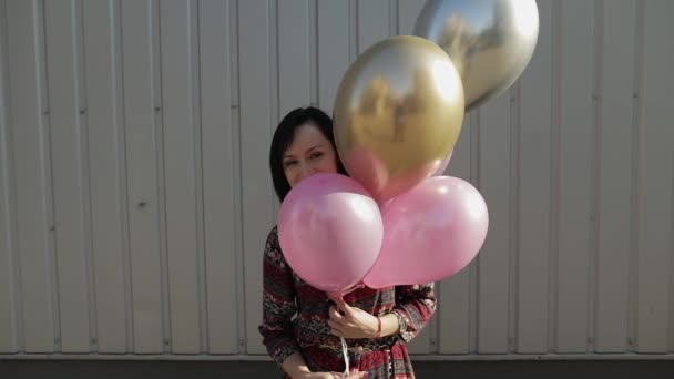 Mulher bonita no vestido segurando balões com hélio ao ar livre à luz do dia — Vídeo de Stock