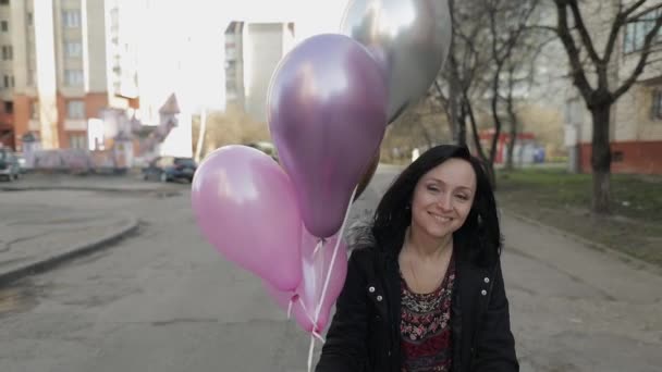 Wanita cantik berjalan di sepanjang jalan memegang balon dengan helium — Stok Video