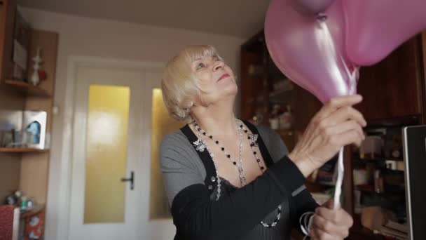 Sevimli büyükanne doğum gününü kutluyor. Çok renkli balonları onun elinde tutan — Stok video