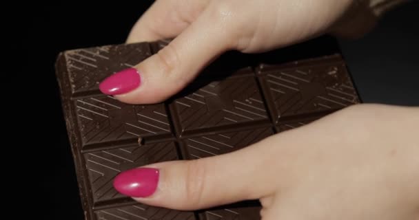 La mujer rompe la barra de chocolate negro. Primer plano de los dedos de mujer — Vídeo de stock