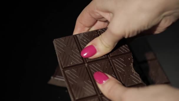 Woman breaks black chocolate bar. Close-up. Slow motion — Stock Video