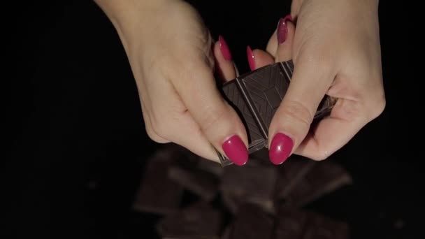Жінка розбиває чорний шоколадний бар. Крупним планом. Повільний рух — стокове відео