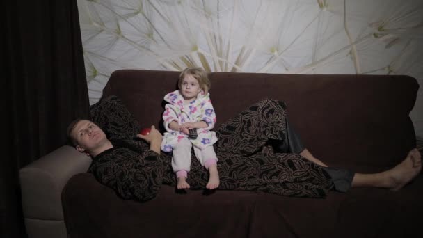 Pequeña hija con su padre viendo películas interesantes y comiendo manzana — Vídeos de Stock