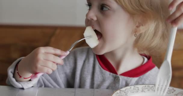Klein meisje eet stukjes verse peer met een vork. Kind eten smakelijke vruchten — Stockvideo