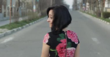 Çiçekler ile bir elbise çekici genç kadın kameraya döner ve gülümsüyor