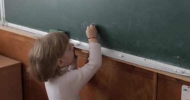 Sınıfta bir tebeşir kullanarak tahta çizim kız. Eğitim süreci