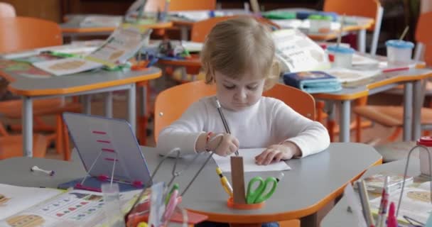 Menina desenho na mesa em sala de aula. Educação. Criança sentada em uma mesa — Vídeo de Stock
