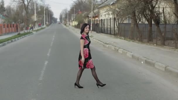Atraktivní mladá žena v šatech s květinami, které chodí po dálnici — Stock video