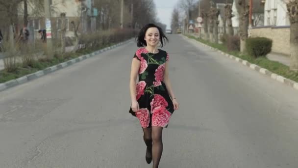 Attraente giovane donna in un vestito con fiori in esecuzione in autostrada — Video Stock