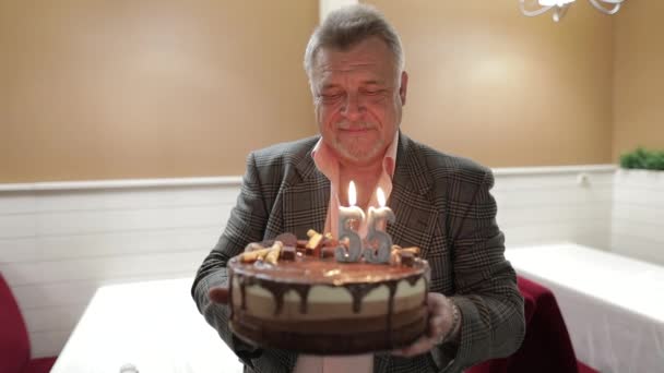 Lycklig respektabel gammal man som håller kakan. Firar. Blåsa födelsedag ljus — Stockvideo