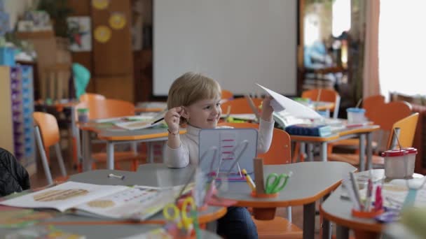 Ragazza che disegna al tavolo in classe. Educazione. Bambino seduto alla scrivania — Video Stock